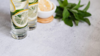selective focus. infused water with lemon, cucumber, mint on gray concrete background. space for text. glass of summer healthy drink