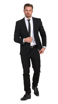 Handsome young man in a black suit walking confidently, isolated on white background