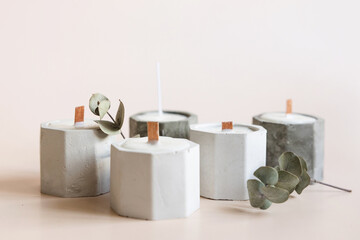 Handmade candles from paraffin and soy wax in concrete plaster candlestick with wooden wick and dry herbal isolated on pastel beige background. Copy space