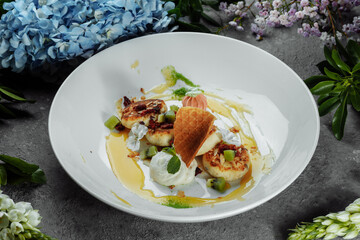 An ideal breakfast. Cottage cheese pancakes with caramel, almonds and cream sauce in a white plate. Ukrainian syrniki