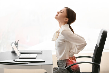 Young businesswoman with pain in lower back at workplace