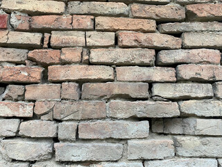 Closeup of grey red old brick of different sizes with cracks and selective focus on foreground