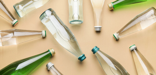 Many bottles of clean water on beige background, top view