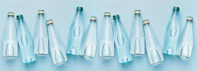 Many bottles of clean water on light blue background, top view