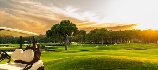 Golf cart on beautiful golf course at sunset - obrazy, fototapety, plakaty