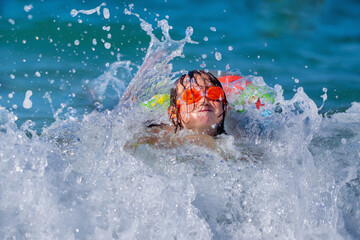 Fototapeta na wymiar Young child girl on breaking wave. Kid in danger during sea swimming.