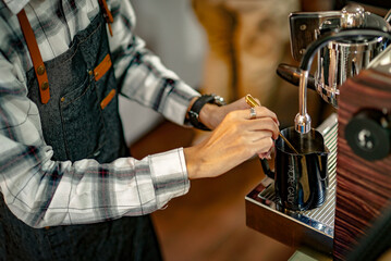 An Asian male owner of a café called Barista Cafe is making coffee.