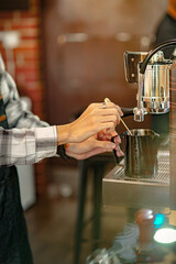 An Asian male owner of a café called Barista Cafe is making coffee.