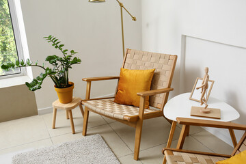 Comfortable armchairs, table and houseplant near light wall