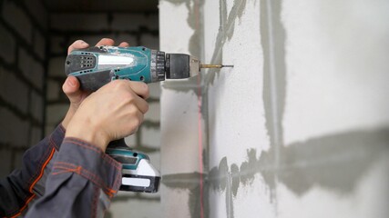 he drill bit slams into the concrete wall of the room in close-up. home renovation concept....