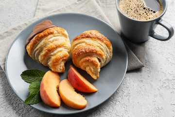 Plate of delicious croissants with chocolate and peach on light background
