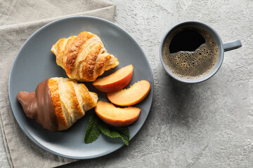 Plate of delicious croissants and cup with coffee on light background