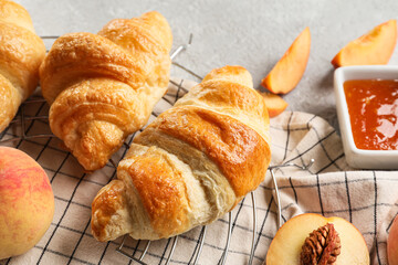 Delicious croissants with peach jam on light background, closeup