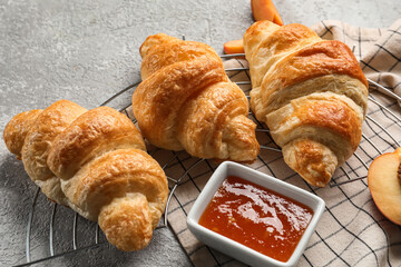 Delicious croissants with peach jam on light background