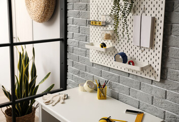 Desk and pegboard with tools on grey brick wall