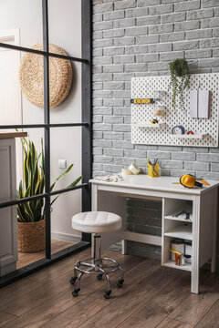 Interior of room with stylish workplace and pegboard on grey brick wall