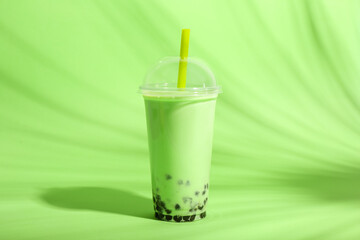 Plastic cup of tasty bubble tea on green background