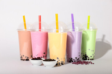 Plastic cups of different tasty bubble tea on light background