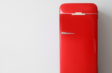 Stylish retro fridge near light wall in room