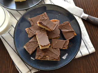 Millionaire's shortbread, caramel shortcake, or millionaire's slice on a black plate.