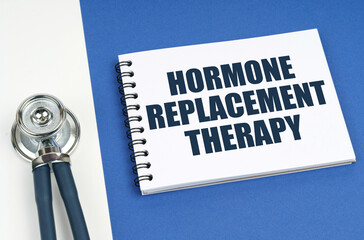 On a blue-white surface lies a stethoscope and a notepad with the inscription - Hormone Replacement...