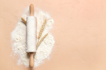 Rolling pin and wheat flour on color background