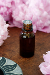 Essential oil bottle with floral scent among pink flowers. Aromatherapy concept..