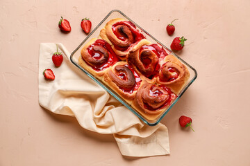 Baking dish with strawberry cinnamon rolls and napkin on beige background