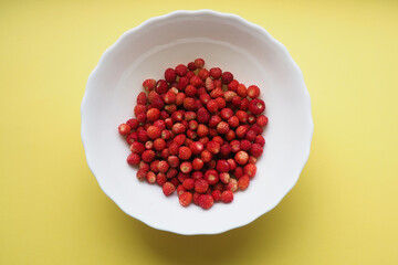 Top view of red strawberries in a white bowl on a foted background