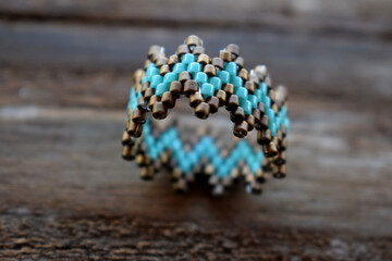 A beaded ring with shinny colors on a wooden surface