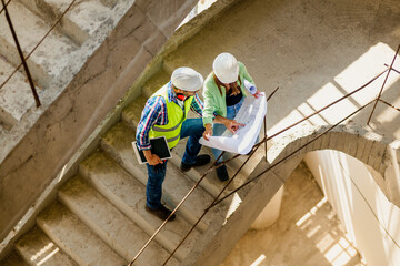 Fototapeta premium Woman architect explaining blueprint to supervisor at construction site. Engineer talking to contractor.