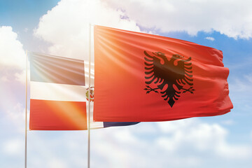 Sunny blue sky and flags of albania and dominican republic