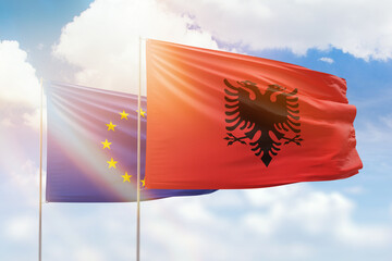 Sunny blue sky and flags of albania and european union