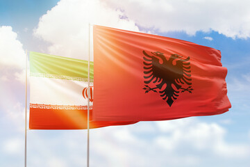 Sunny blue sky and flags of albania and iran