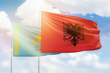 Sunny blue sky and flags of albania and kazakhstan