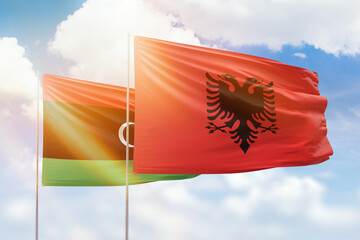 Sunny blue sky and flags of albania and libya