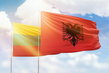 Sunny blue sky and flags of albania and lithuania