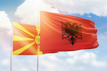 Sunny blue sky and flags of albania and north macedonia