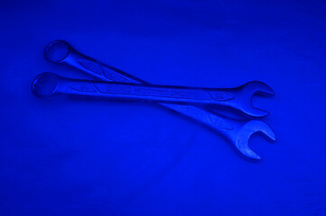 Two spanners made of chrome vanadium steel on a soft surface covered with a bit of smoke under the blue light.