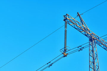 High voltage electricity tower with power line against blue sky. Overhead electric power line with...
