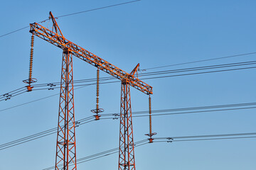 High voltage electricity tower with power line against blue sky. Overhead electric power line with insulators. Electricity generation, transmission, and distribution network. Indastry landscape.