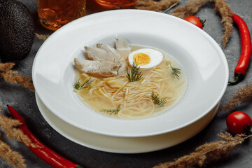 Chicken soup with noodles and vegetables in white bowl