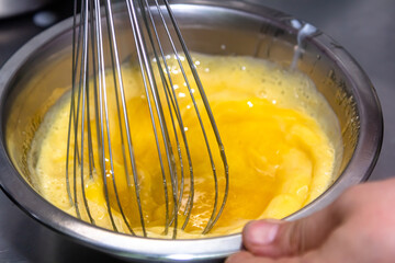 whisking egg yolks and sugar in a bowl