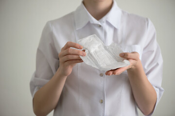 Woman in medical uniform with pads for menstruation in hand. Menstruation and hygiene concept; monthlies, women's periods. Close-up, selective focus.