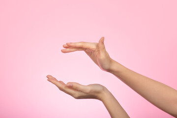 Woman's hand on pink background. Female hands with air between, ready for product placement...