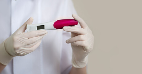 Doctor in medical uniform holds disposable pregnancy or ovulation electronic test. Healthcare concept. Close-up, selective focus