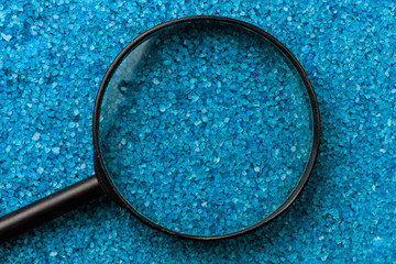 Magnifying glass on the background of sea aromatic bath salts. Concept of searching for romantic...