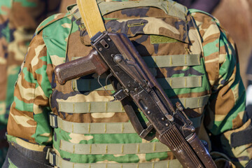 Automatic rifle without a magazine on the back of a military man. Background with selective focus...