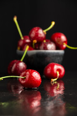 Close-up of wet cherries, reflected, selective focus, black background, vertical, with copy space