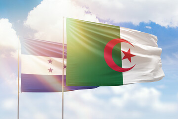 Sunny blue sky and flags of algeria and honduras